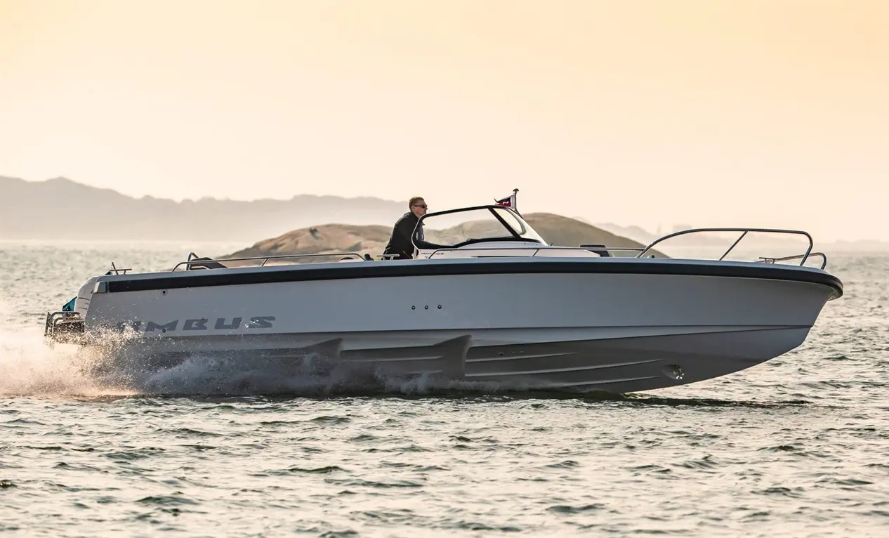 A sleek boat with the name "Nimbus" navigates through water, with a person steering against a serene horizon.
